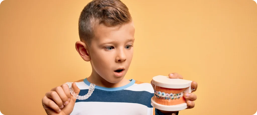 Enfant tenant un modèle dentaire avec appareil orthodontique